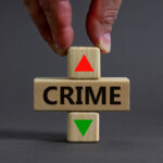 Crime rate symbol. Businessman holds a wooden cubes with up arrow. Wooden block with the concept word Crime. Beautiful grey table grey background. Business and crime rate concept. Copy space.
